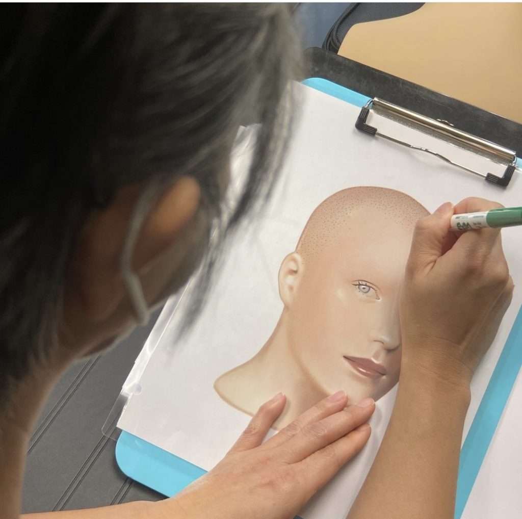 Girl sketching a bald headed portrait on whiteboard